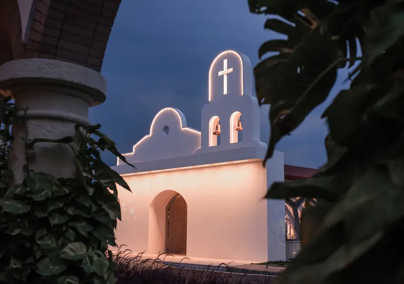 Campanario de la capilla al anochecer entre el follaje de los jardines de la hacienda