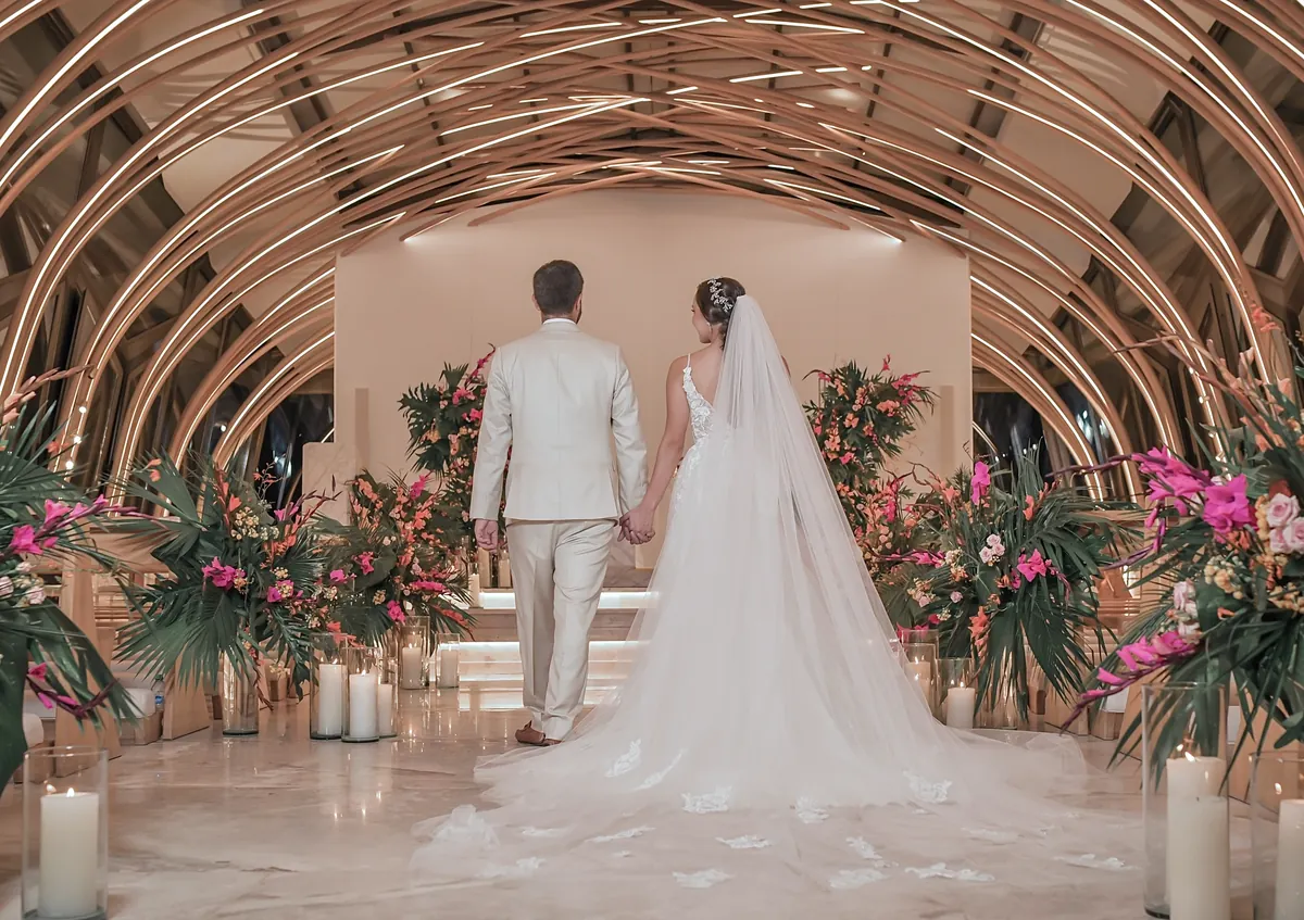 Interior de la capilla con la bóveda de madera iluminada mientras los novios recorren el pasillo