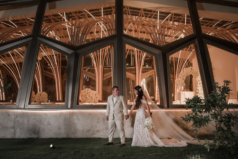 Nave de cristal y madera de la capilla iluminada de noche durante una boda